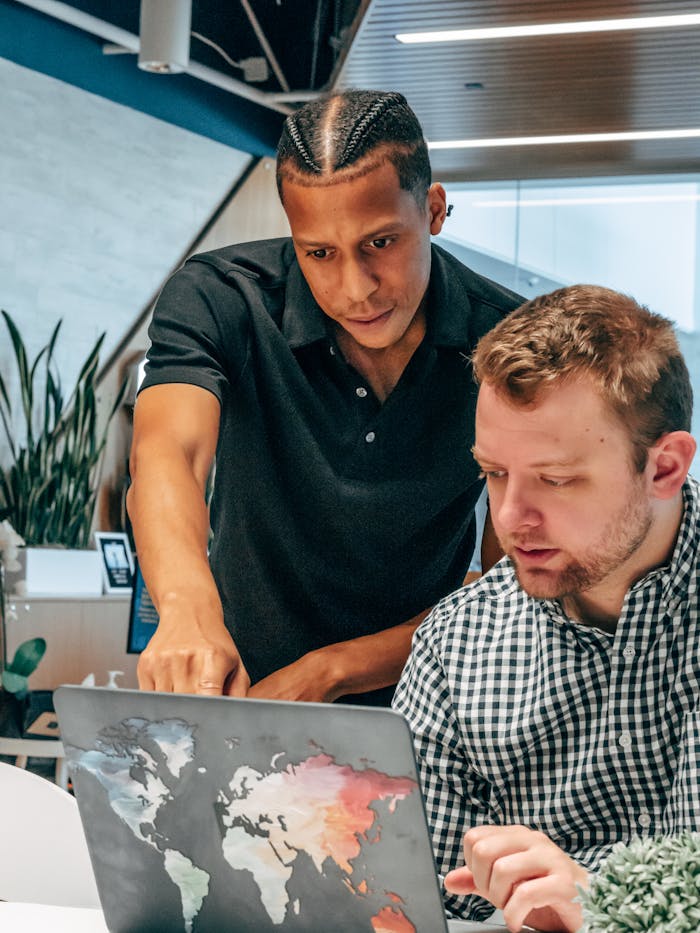 Two diverse colleagues collaborating over a laptop in a modern office environment.